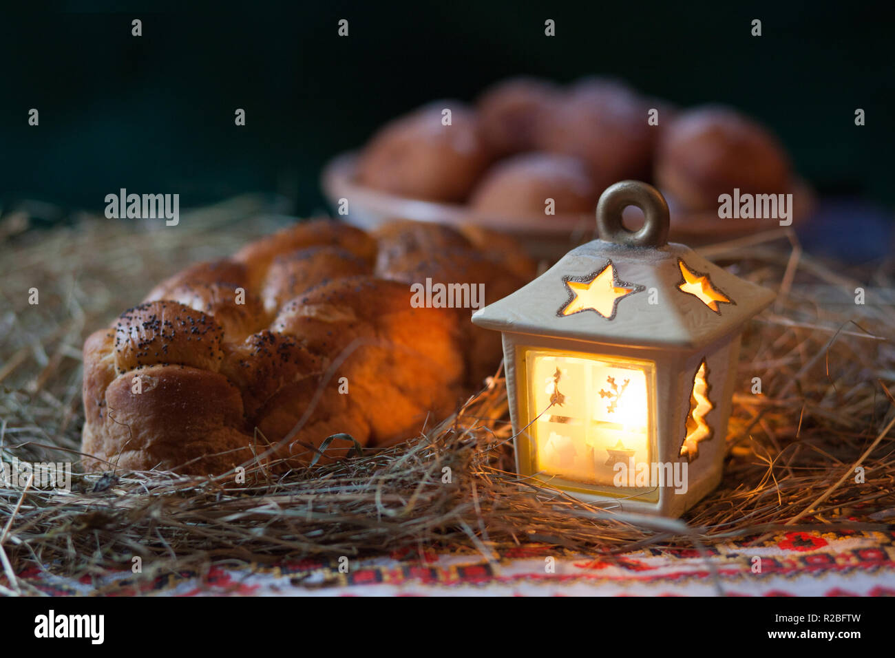 Christmas still life. Donuts and kalach on the table covered with hay. Traditional East Slavic bread. Stock Photo