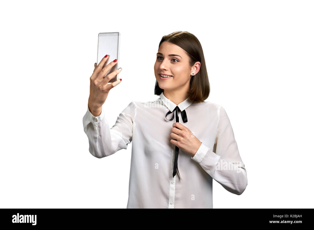 Smiling woman with smartphone on white ackground. Cheerful lady in elegant blouse talking via internet, isolated on white background. Stock Photo