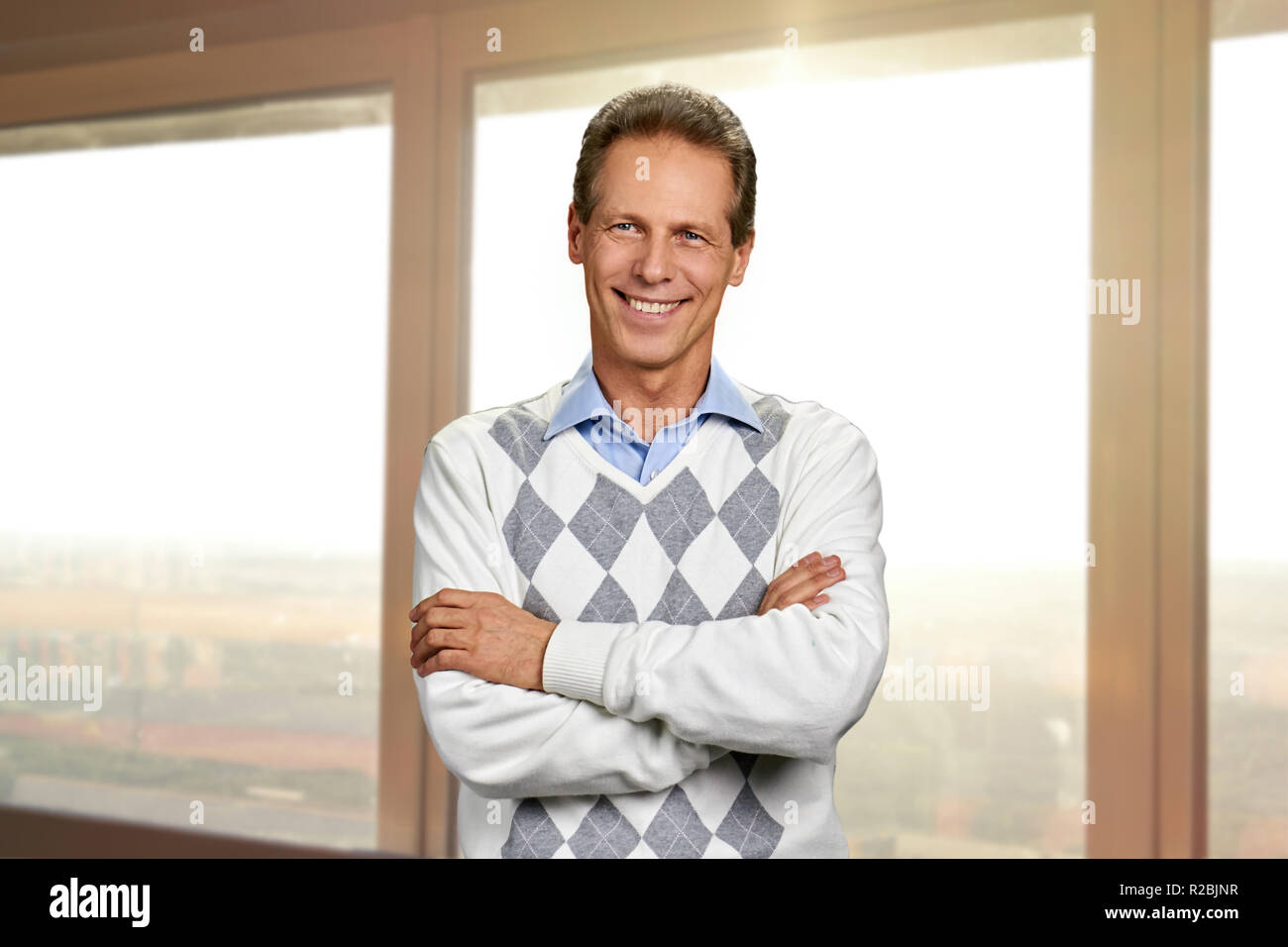 Happy mature man with crossed arms. Portrait of cheerful man standing ...