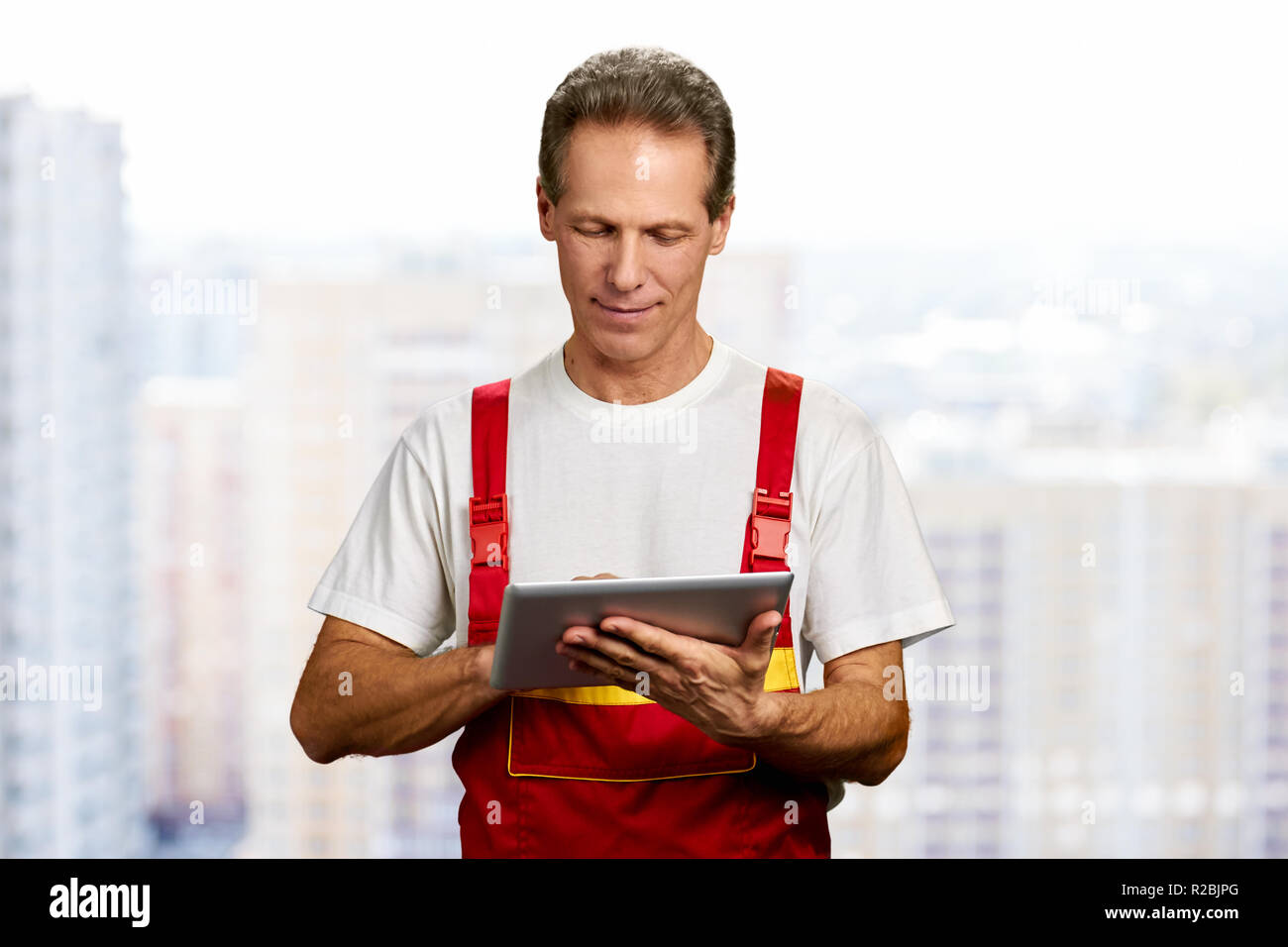 Manual worker using digital tablet. Middle-aged builder working on computer tablet. People, construction, technology. Stock Photo