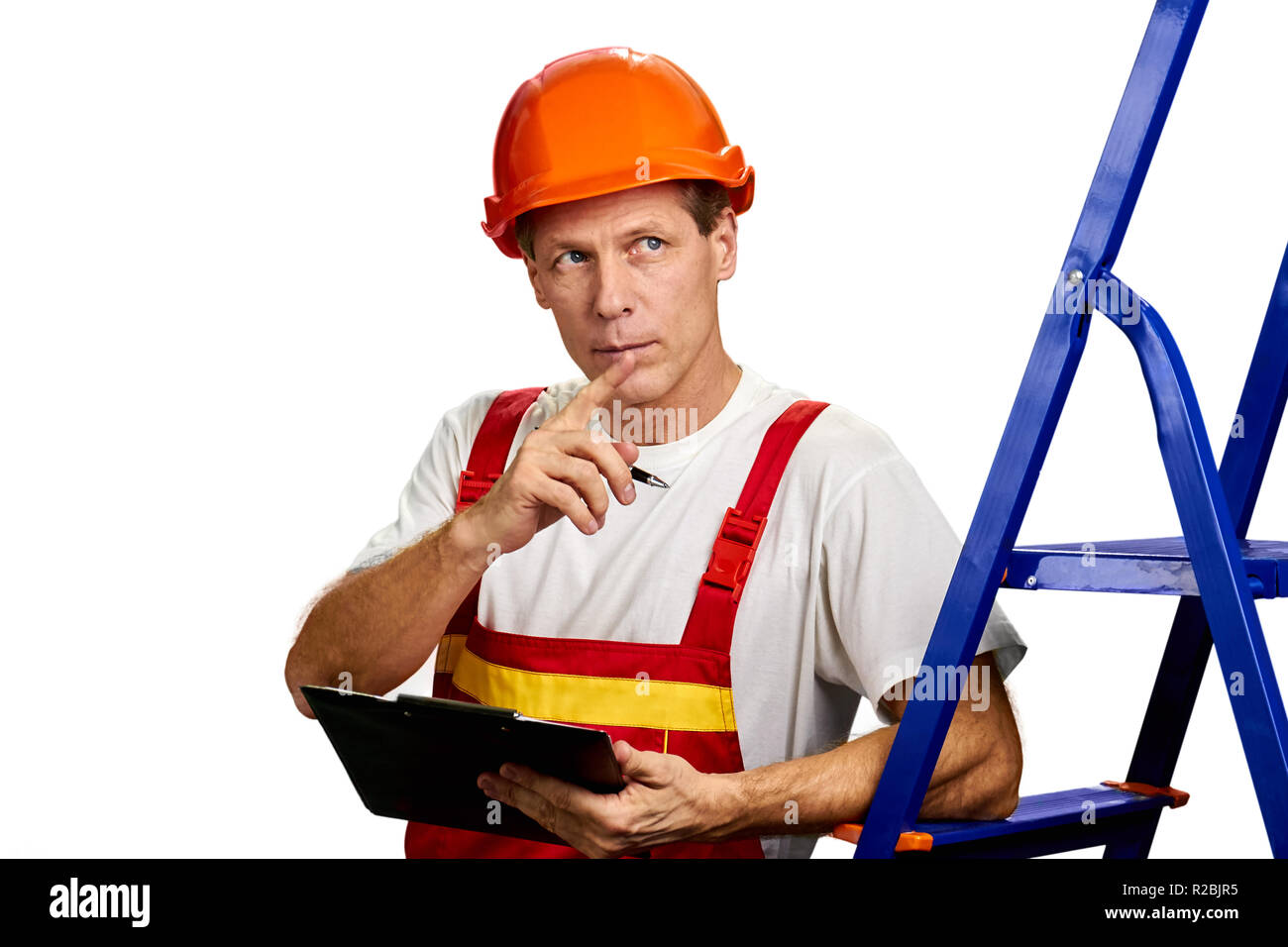 Thoughtful foreman on white background. Handsome middle-aged building engineer in helmet with folder over white background. Supervisor checking an obj Stock Photo