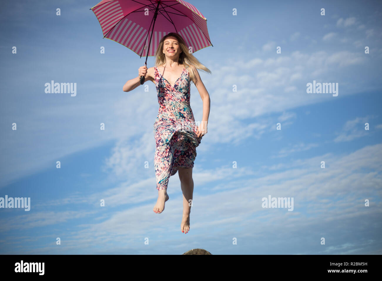 Young attractive happy female jumping in sky with umbrella Stock Photo ...