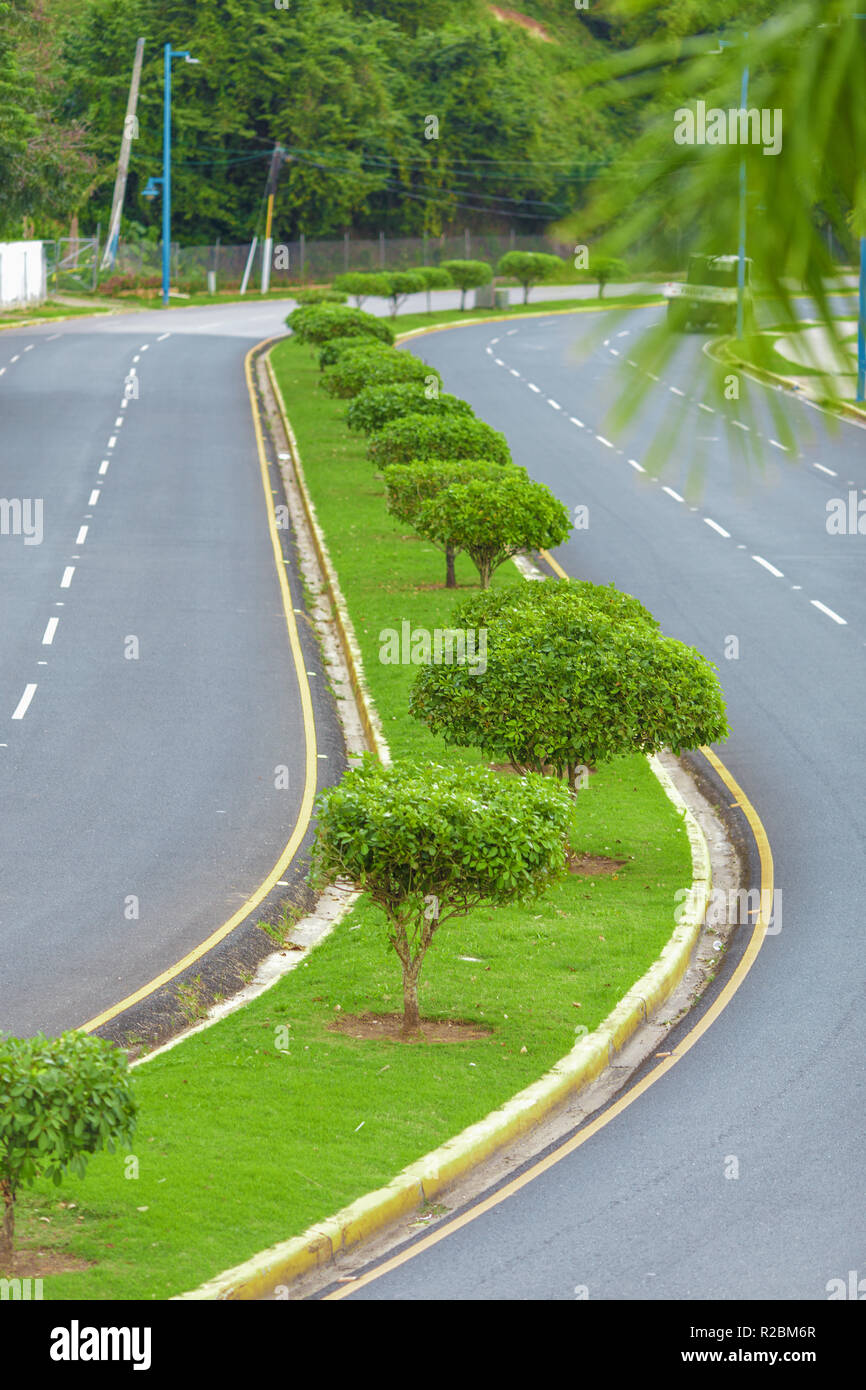 road with a dividing strip of green grass and trees Stock Photo Alamy