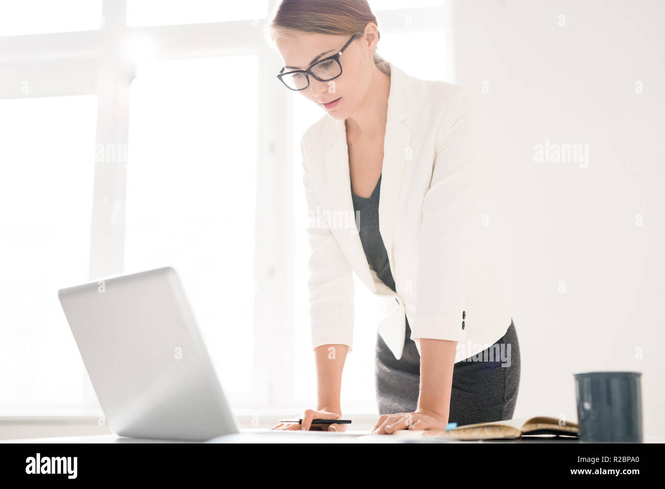 Concentrated female manager viewing data on laptop Stock Photo
