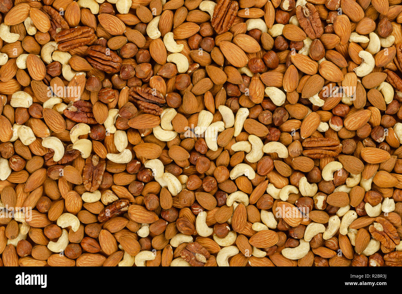 Mixed nuts, surface and background. Snack mix of dried almonds, cashews, hazelnuts and pecans. Trail mix, student food or fodder. Stock Photo