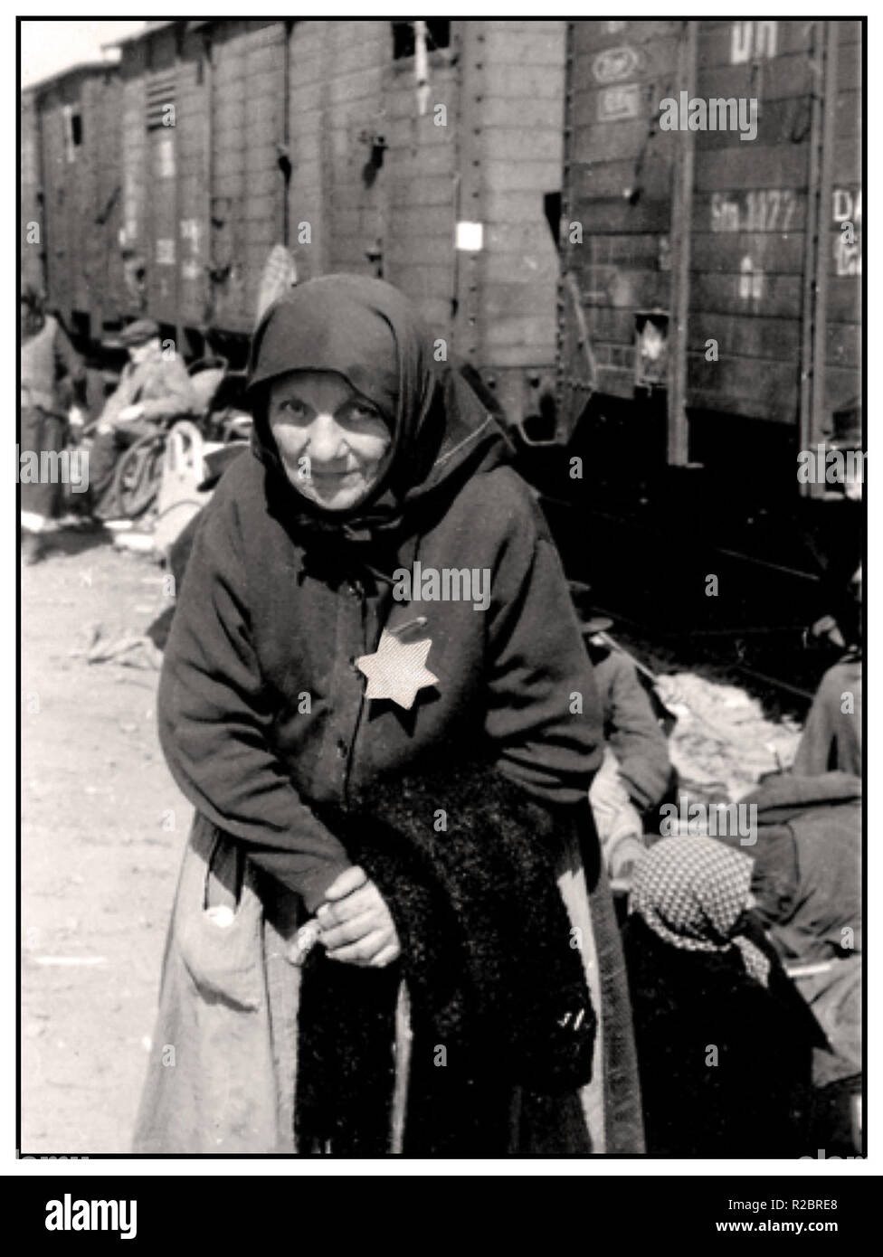 Auschwitz-Birkenau Elderly Hungarian Jewish lady, previously interned at either the Tét or Berehovo Ghetto, arrives by an insanitary cattle car at Auschwitz II, also known as  Auschwitz-Birkenau. She is wearing the mandatory Nazi designated yellow star. Her haunting expression to camera is a tragic enduring reminder from history of the imminent unspeakable fate for her and many millions like her, whose only ‘crime’ was to be Jewish .... Auschwitz-Birkenau Poland Stock Photo