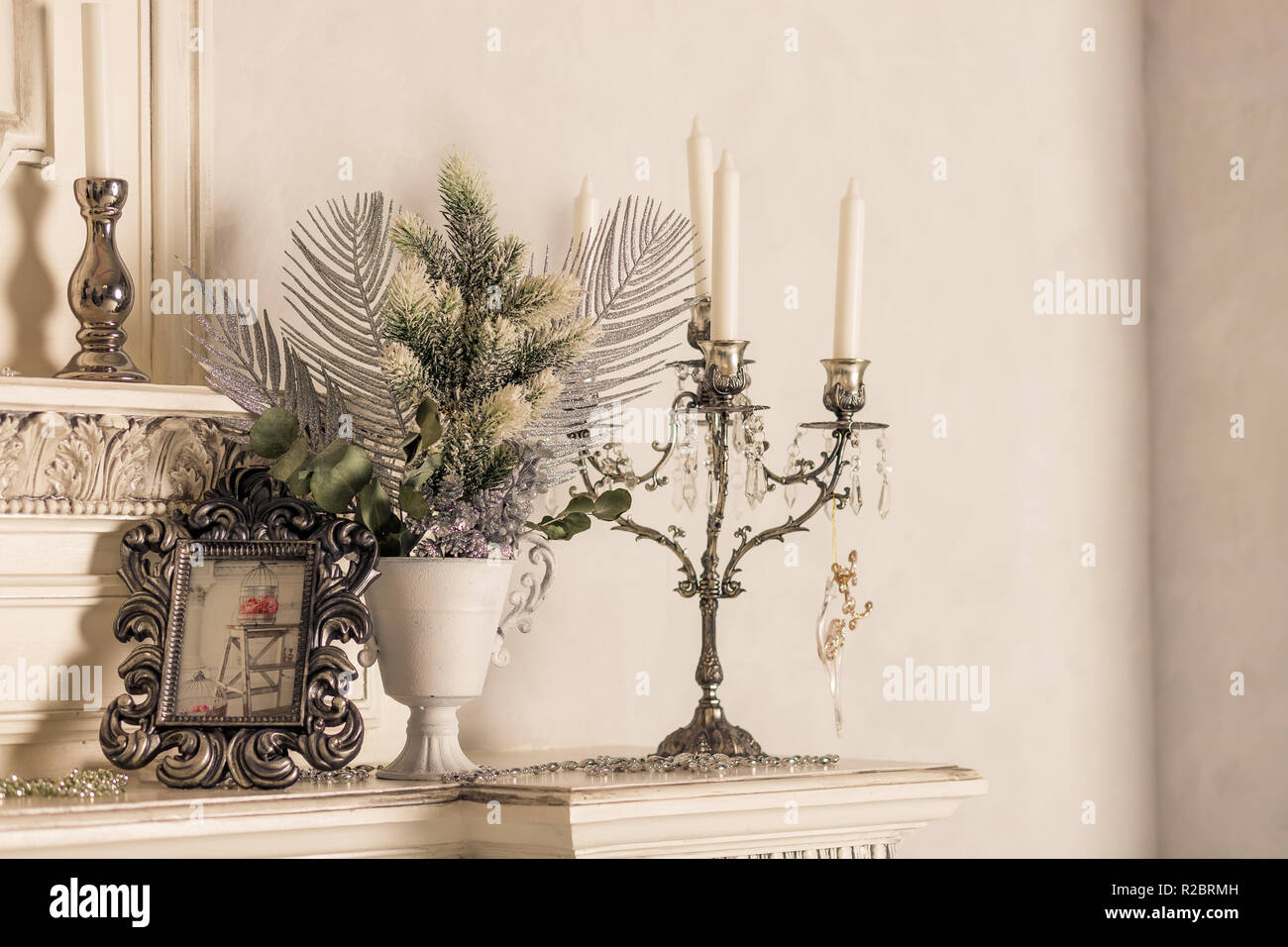 Christmas decoration with candles on shelf, white wall.Retro silver