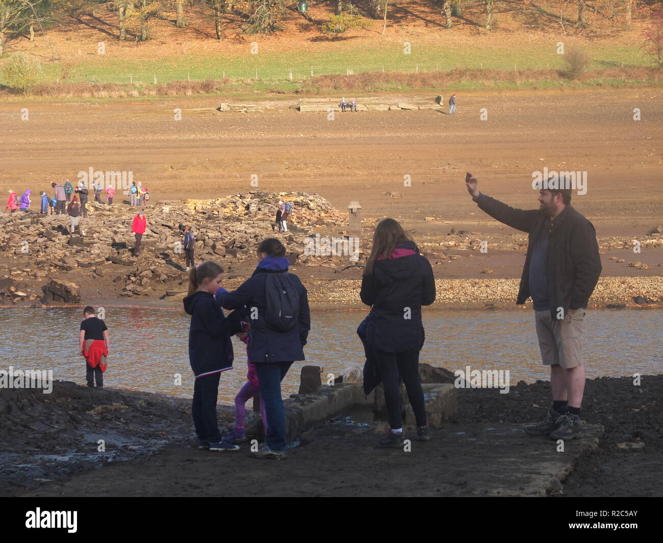 Family taking photo on what is normally the bottom of Ladybower Reservoir. Crowds explore remains of Derwent Village, exposed following 2018 heatwave. Stock Photo