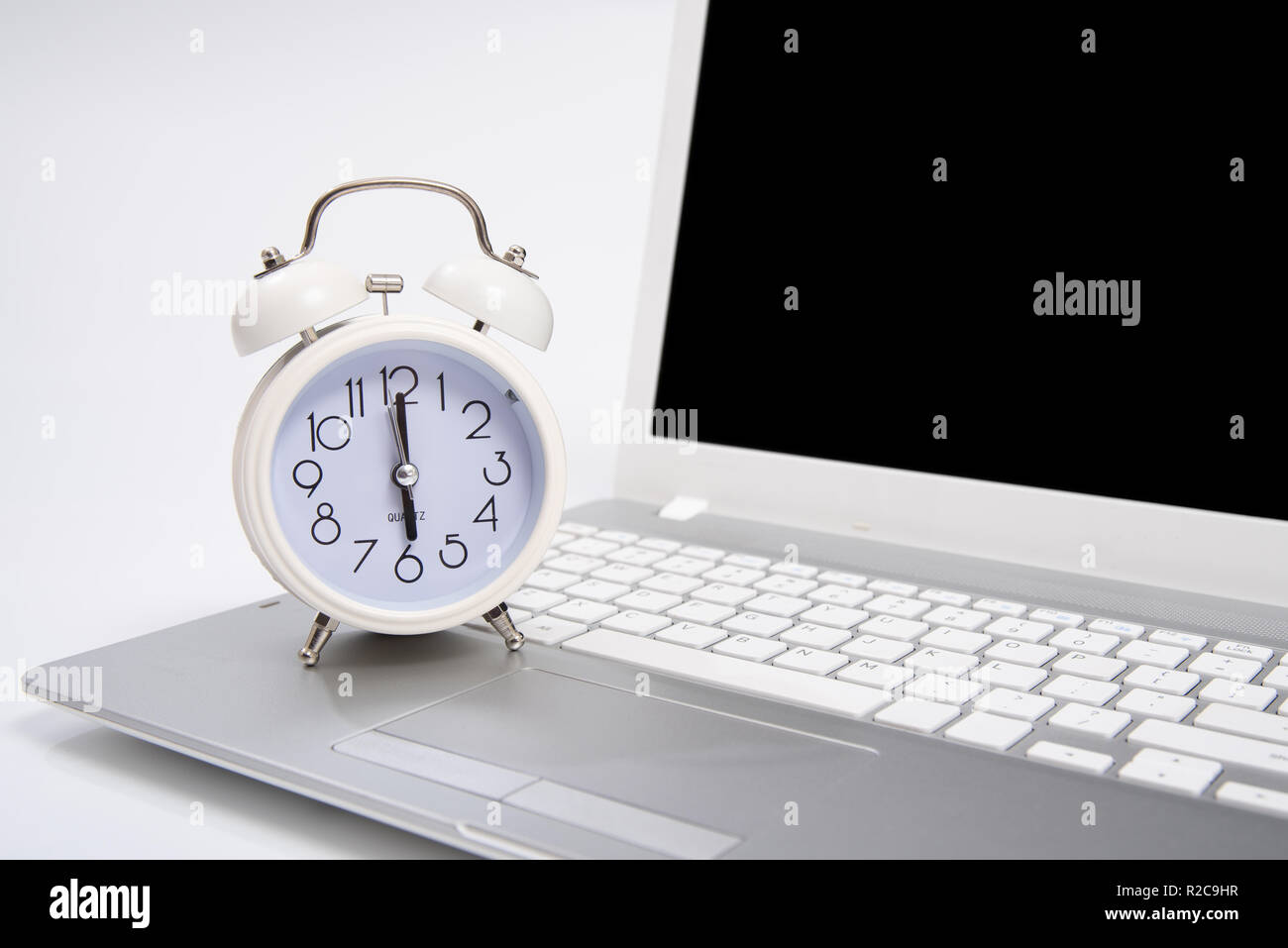 Alarm clock and portable computer put on the desk, with white
