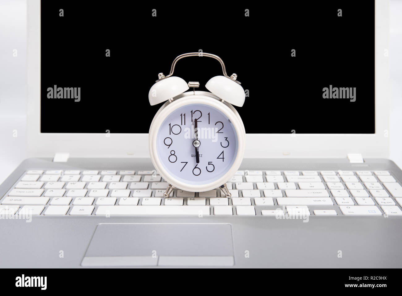 Alarm clock and portable computer put on the desk, with white