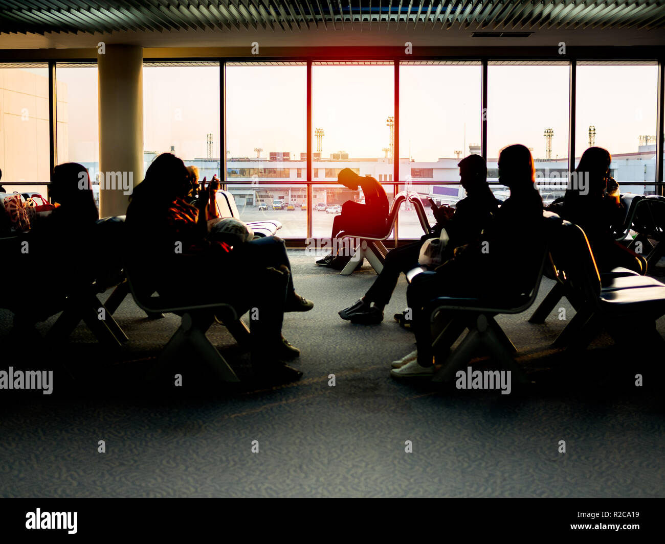 BANGKOK, THAILAND - November 1, 2018 : Passenger sitting on waiting chairs near the window glass waiting for boarding to the aircraft on sunset in eve Stock Photo