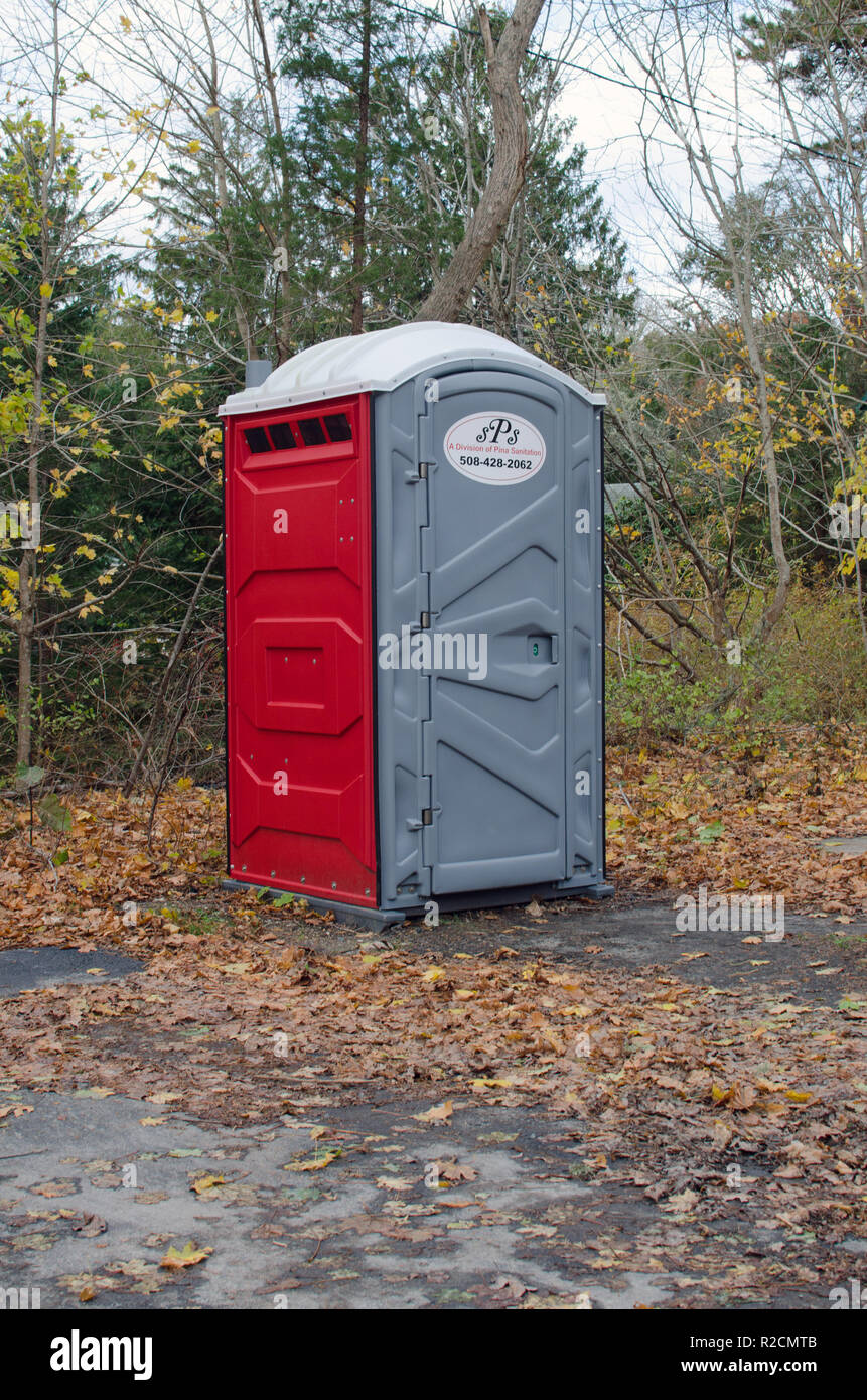 Portable bathroom chemical toilet lavatory restroom with a poly plastic moulded housing with door in wooded area by Falmouth Shining Sea Bikeway Stock Photo