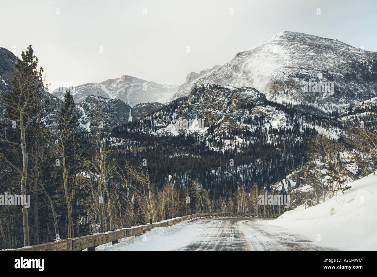 A snowy road winds through the Rocky Mountains in winter Stock Photo