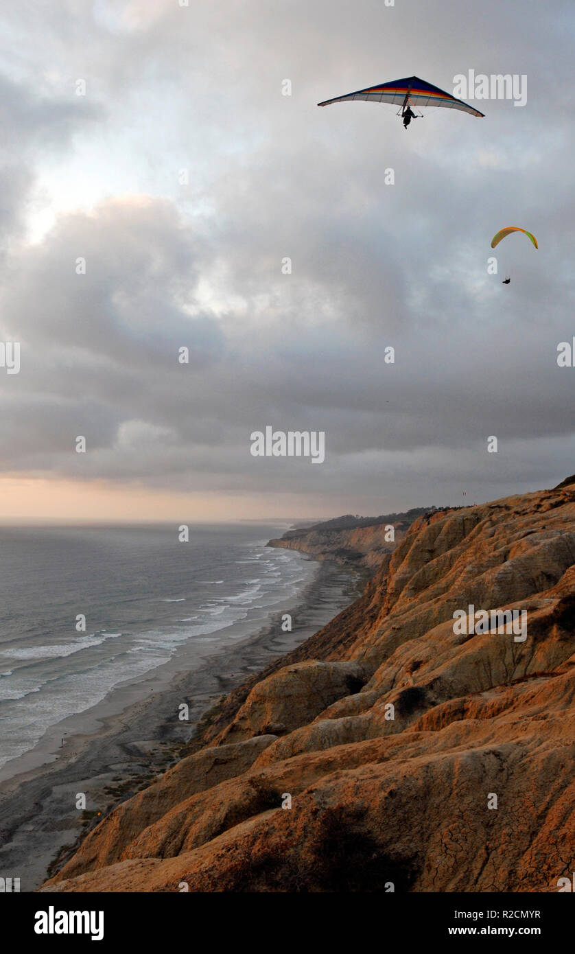 A hang glider and paraglider soar above the Torrey Pines cliffs on the