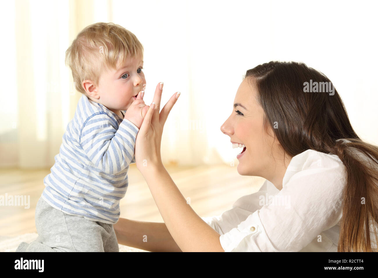 Baby kissing his mother finger on the floor in a room Stock Photo