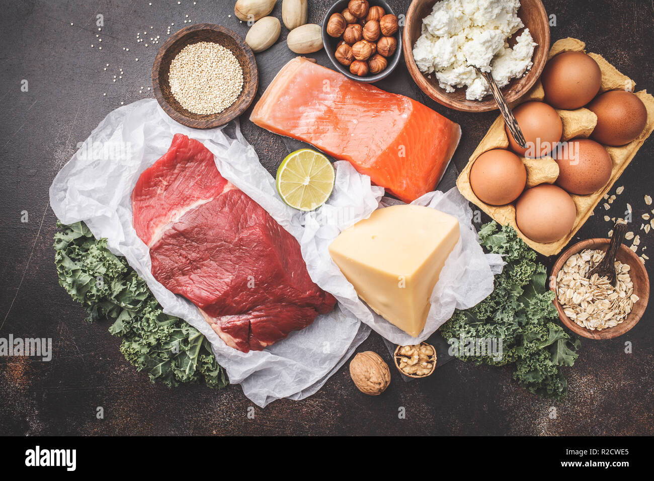 Balanced diet food background. Protein foods: fish, meat, eggs, cheese, quinoa, nuts on dark background, top view. Stock Photo