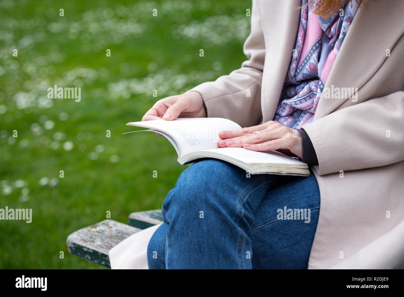 the girl is sitting on a park bench and reading a book Stock Photo - Alamy