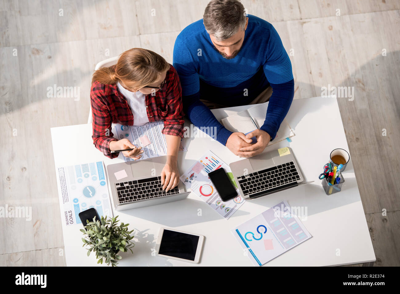 Serious colleagues using laptops while working with data Stock Photo