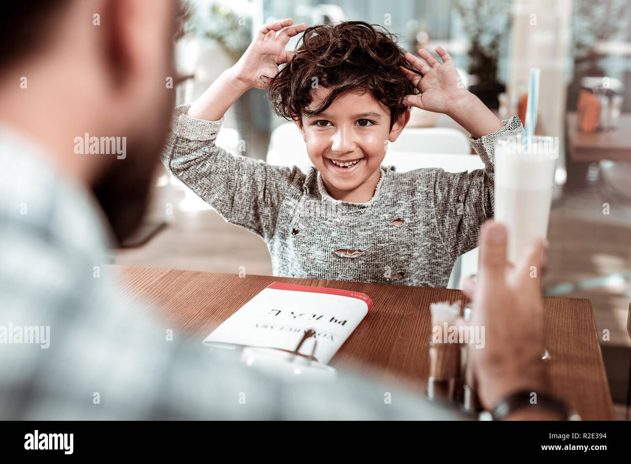 Happy son drinking milk shake spending time in cafeteria with father Stock Photo