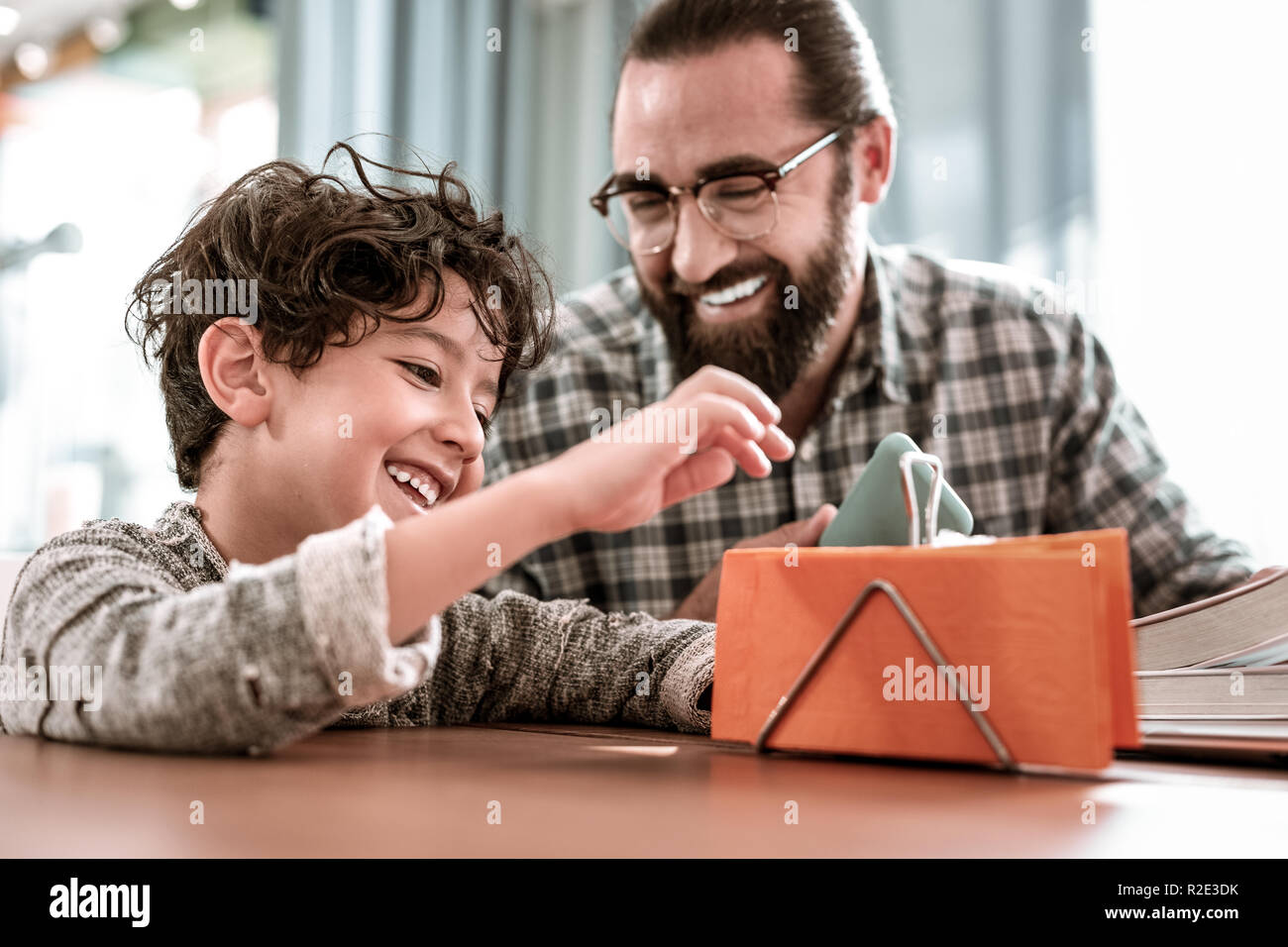 Smiling dark-haired preschool boy sitting near his loving father Stock ...