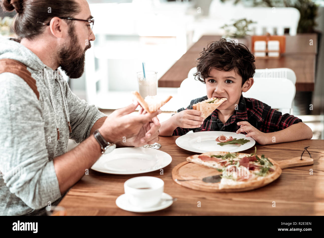 Happy father and son having lunch in cafeteria eating yummy pizza Stock Photo