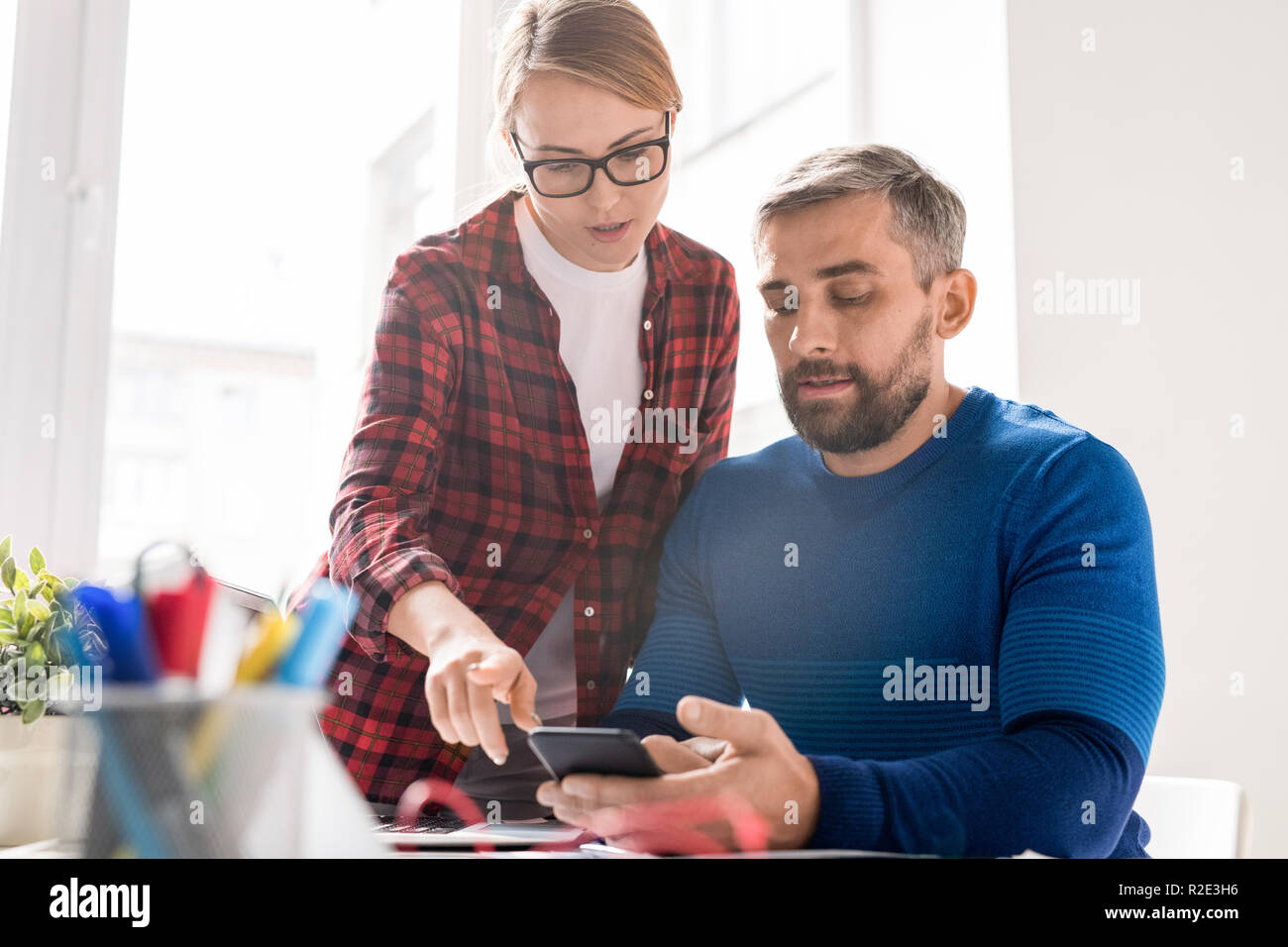 Lady analyzing new smartphone app with colleague Stock Photo