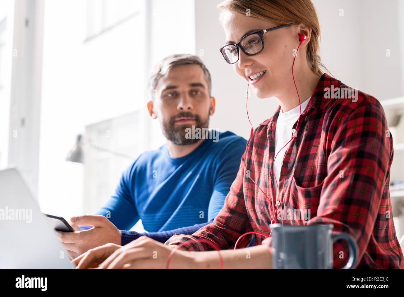 Cheerful female programmer focusing on coding Stock Photo