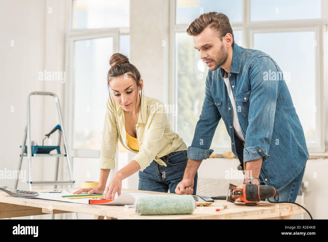 young couple looking at blueprint during house repair Stock Photo