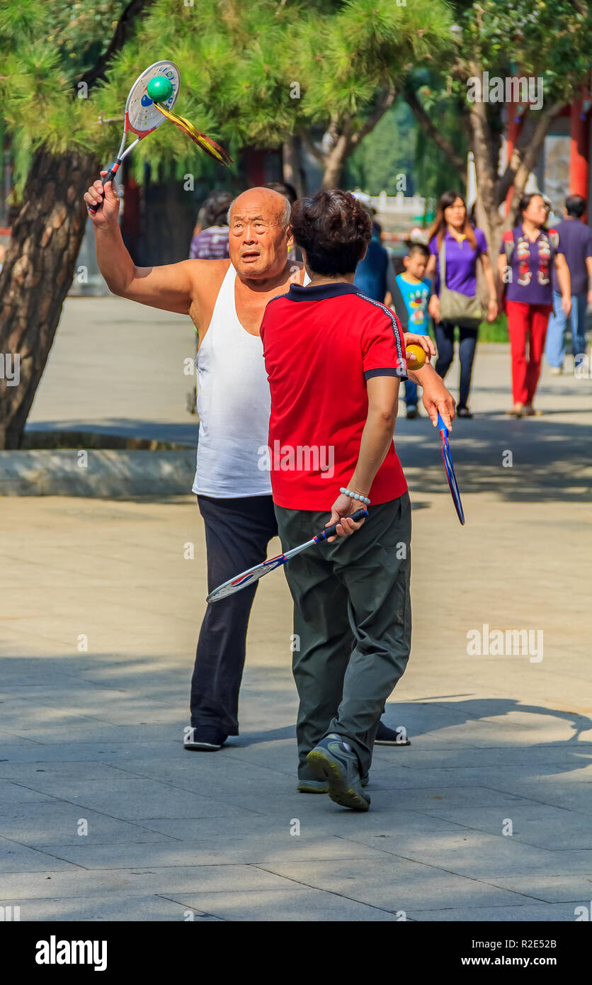 Beijing, China - September 20, 2013: Elder couple playing Chinese game of Jianzi with a colorful feather shuttlecock and a racket in Beihai Park on a  Stock Photo