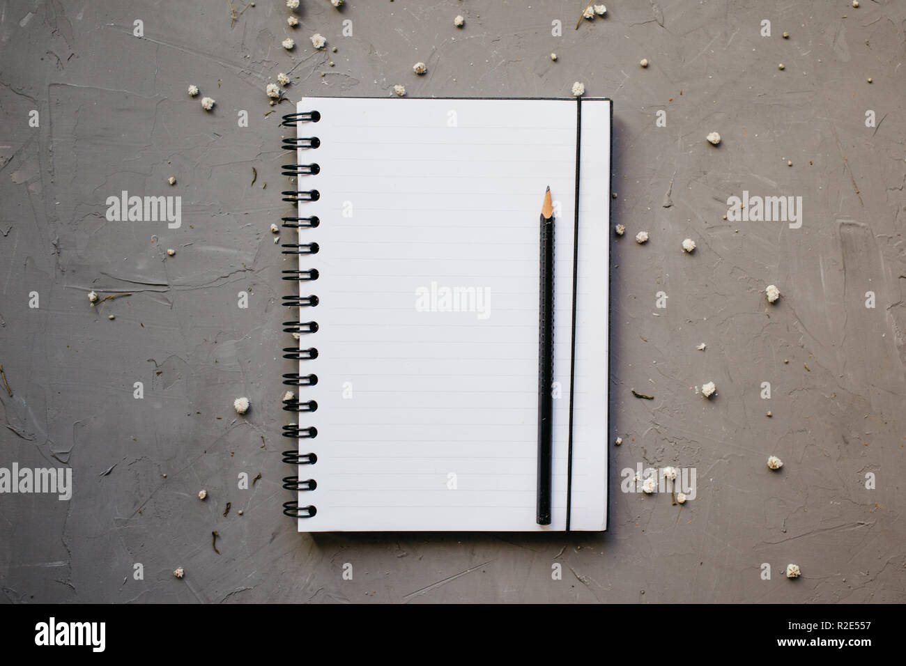 Mock-up with clean notepad and small white flowers, top view. Flat lay ...