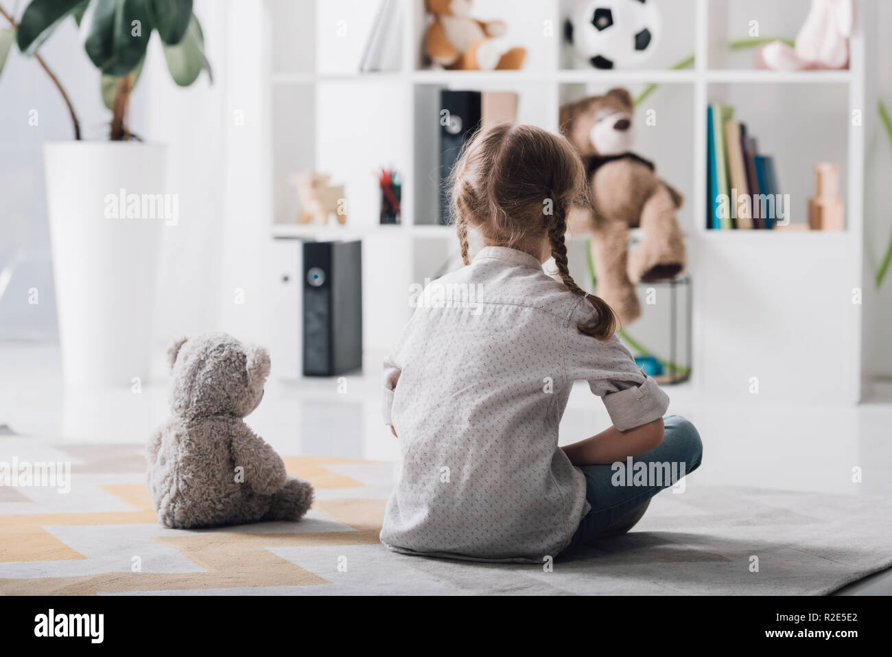 rear view of lonely little child sitting on floor with teddy bear Stock ...