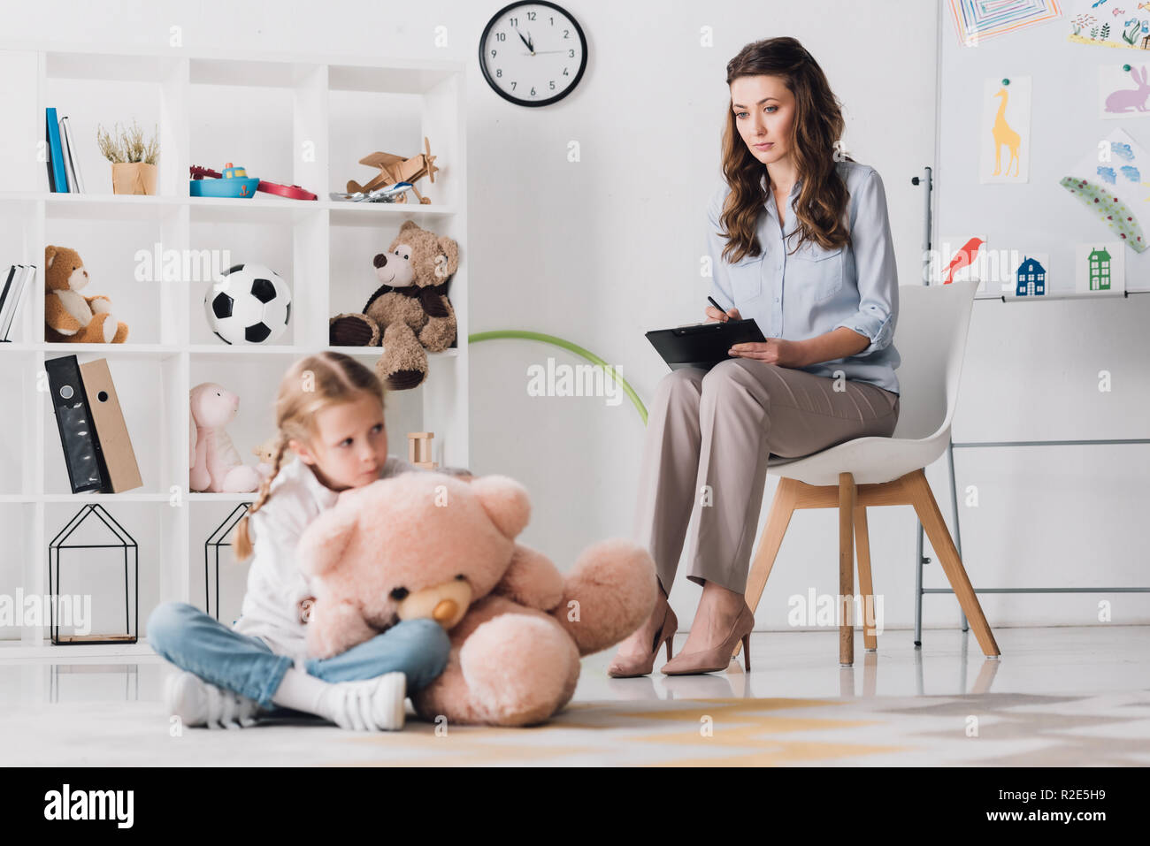 depressed little child with teddy bear sitting on floor with ...