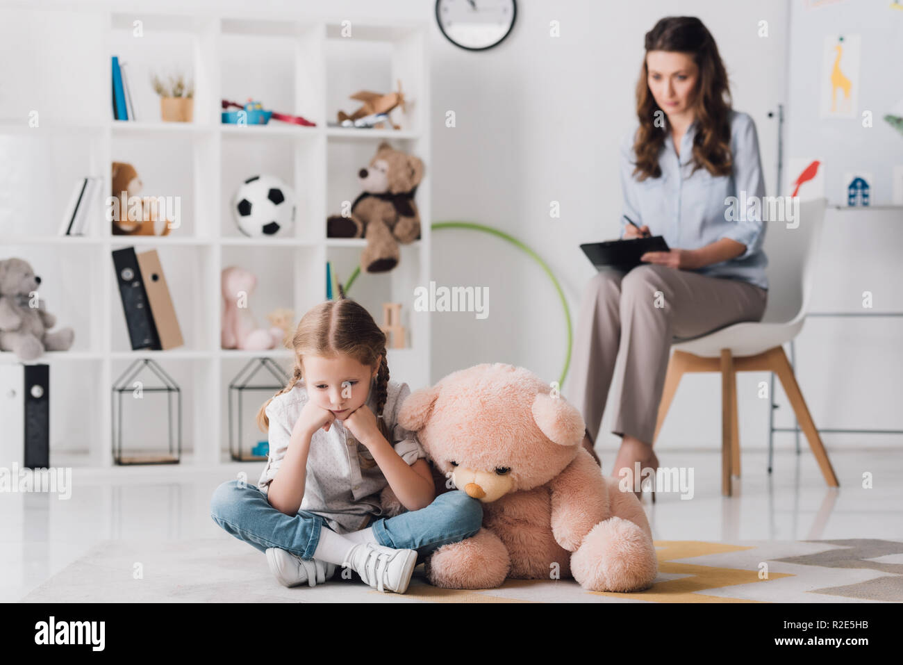 depressed little child with teddy bear sitting on floor with blurred ...