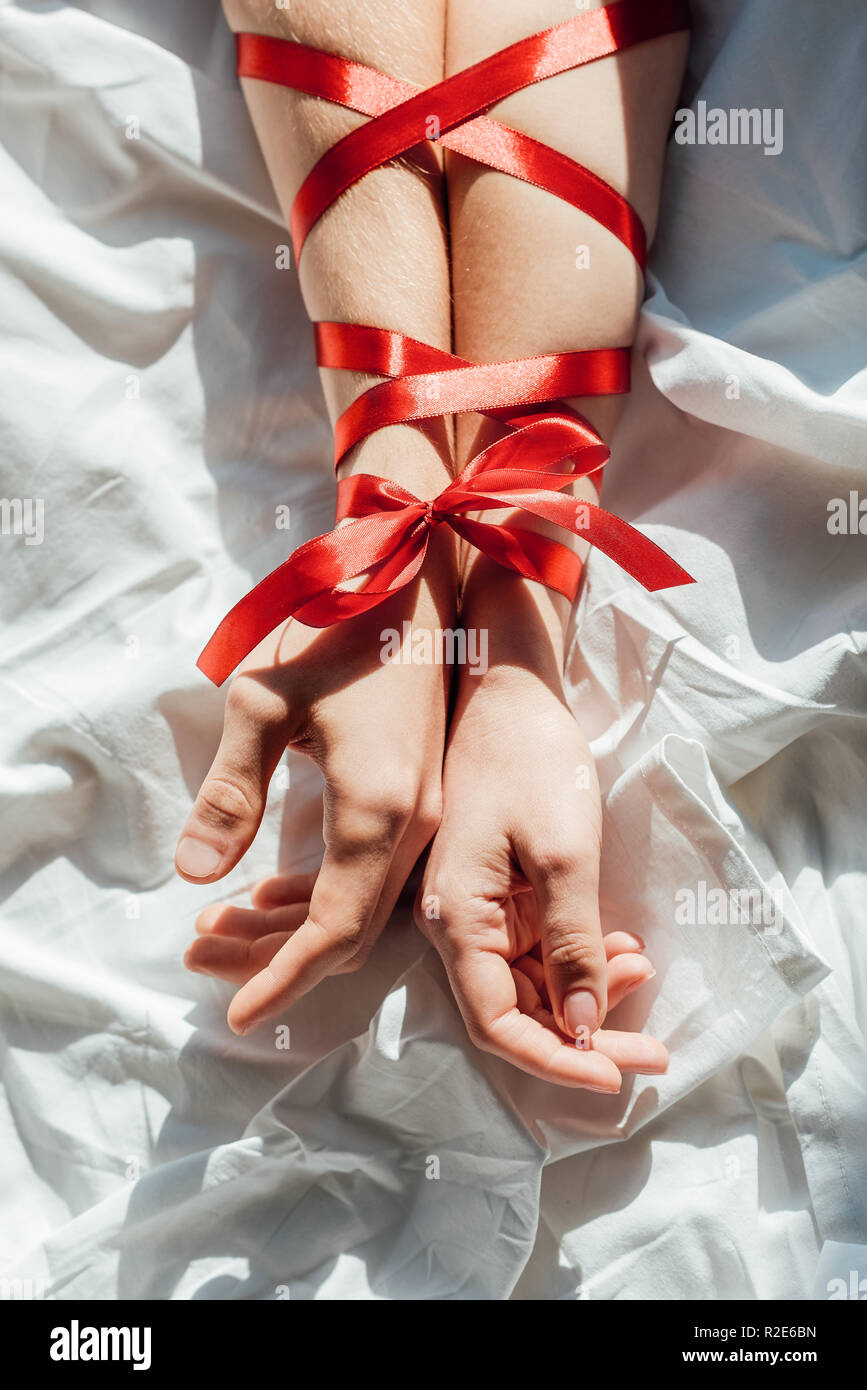 cropped shot of male and female hands tied with red ribbon on bed Stock  Photo - Alamy