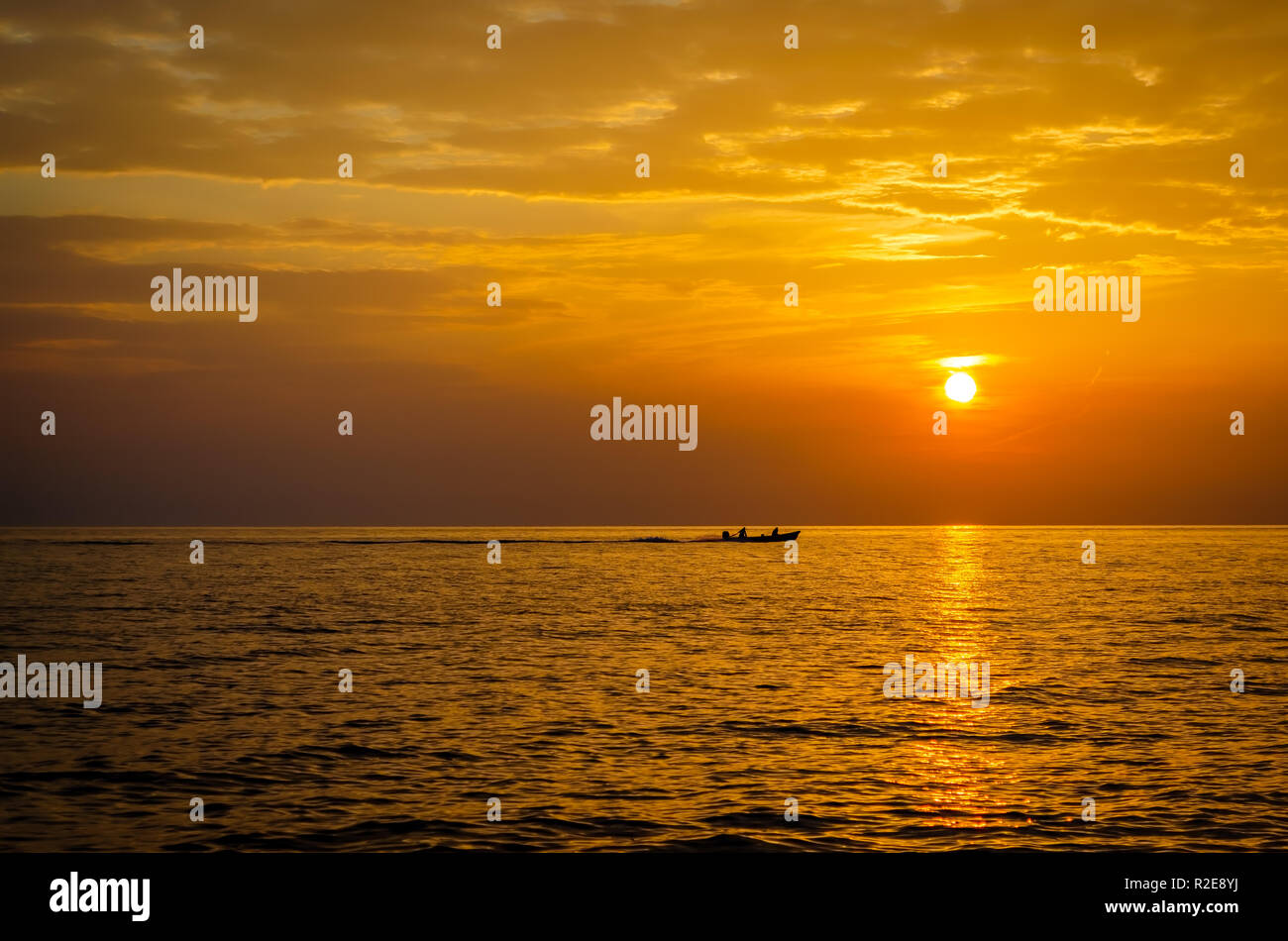 Silhouette of fishermen in a boat starting their day during sunrise. Stock Photo