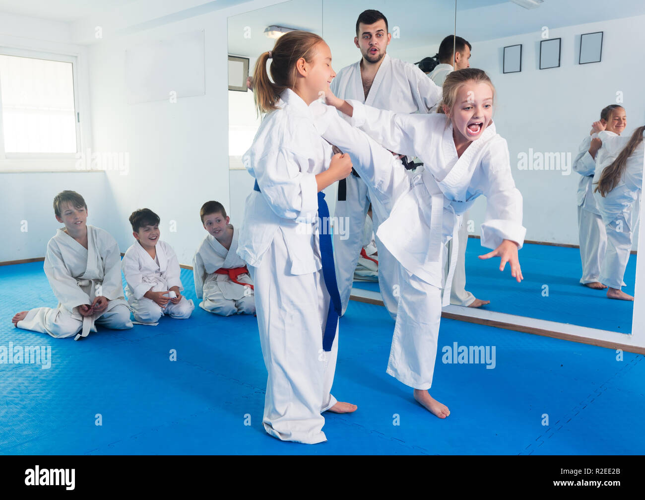 Young girls fighting in pair to use new karate techniques during class Stock Photo