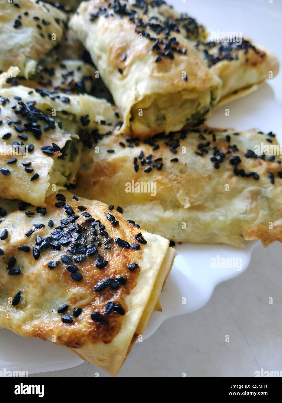 Cutted lavash pieces with vegetables. Burek with spinach and cheese and black cumin. Yufka Stock Photo