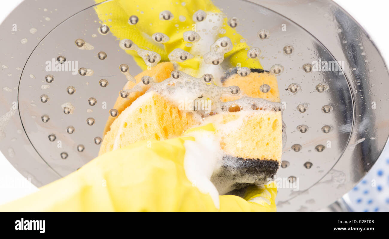 Closeup of shower head with foam being disinfected by person with