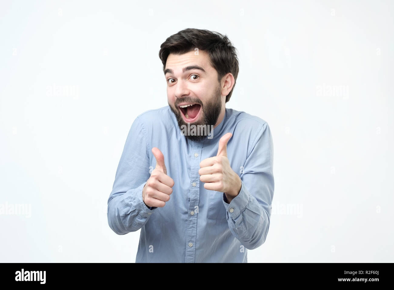 Smiling hispanic man showing both thumbs up and looking at camera. Stock Photo