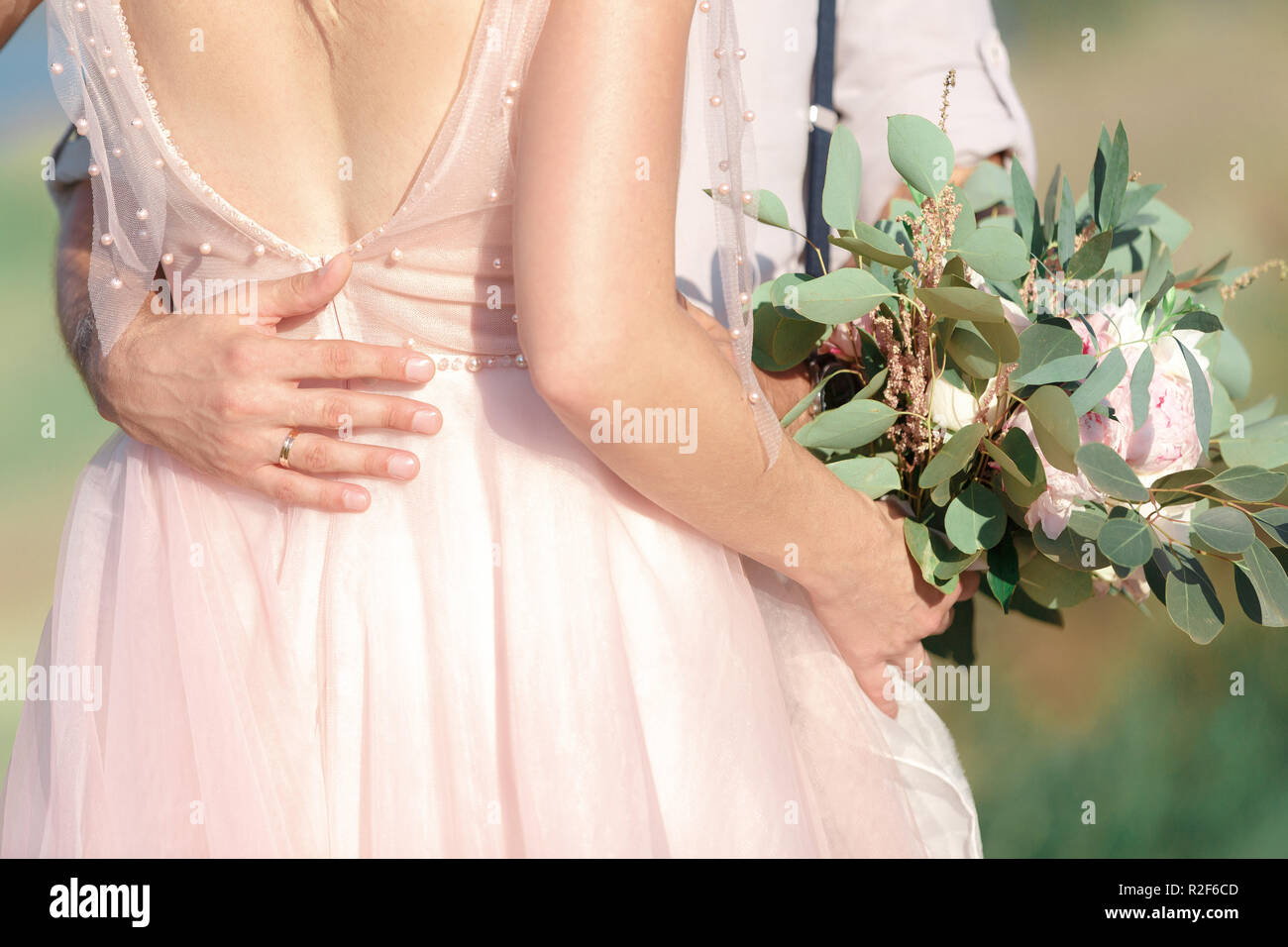 Hands of the bride and groom with wedding bouquet Stock Photo - Alamy