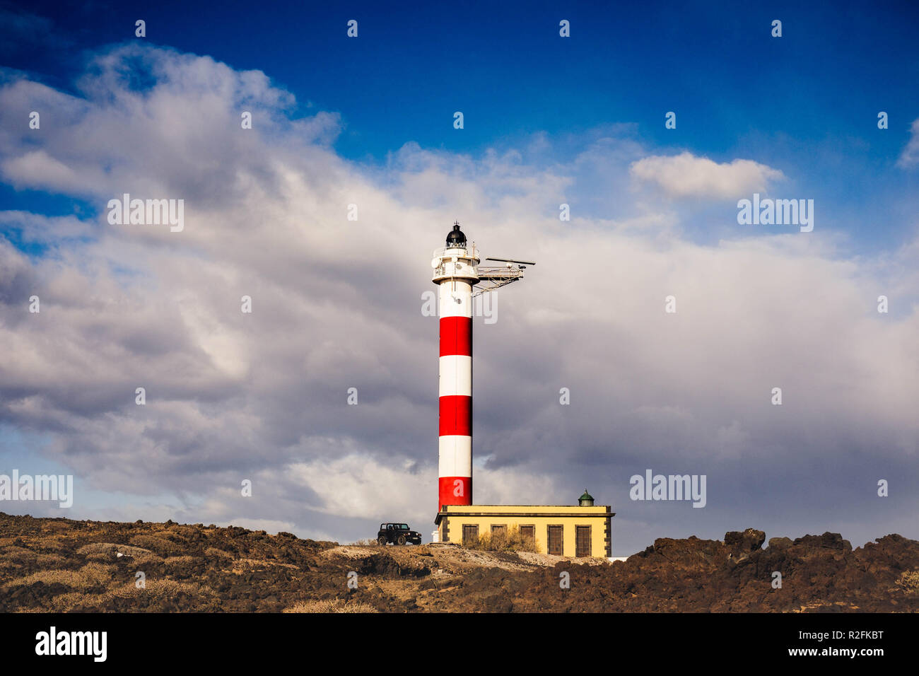 Spirit of adventure and freedom concept. Black offroad car open parked down a lighthouse in Tenerife. Beautiful sky and nature around. Stock Photo