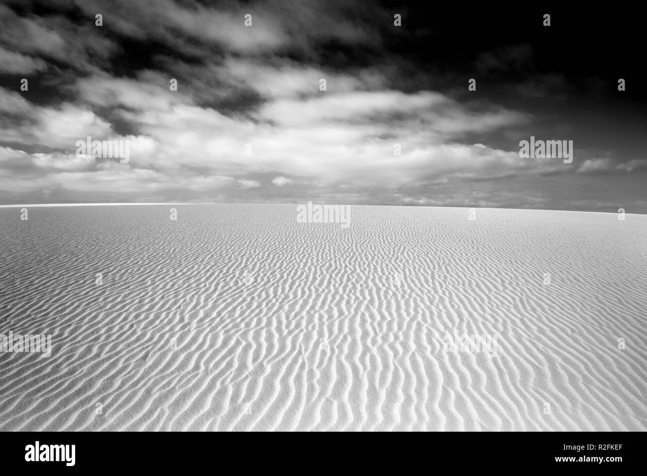 fine art landscape wallpaper of desert dunes in black and white. pattern with straight lines with dramatic sky with clouds Stock Photo