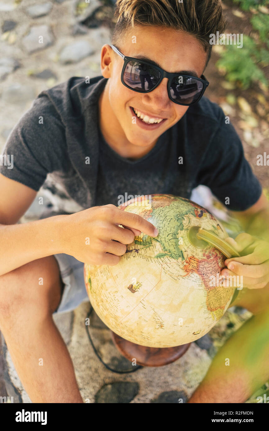 handsome young boy with a eatrth globe choose his next travel vacation adventure destination. new modern people love wanderlust concept and expore the world with no planned holiday. backpack millennial generations Stock Photo