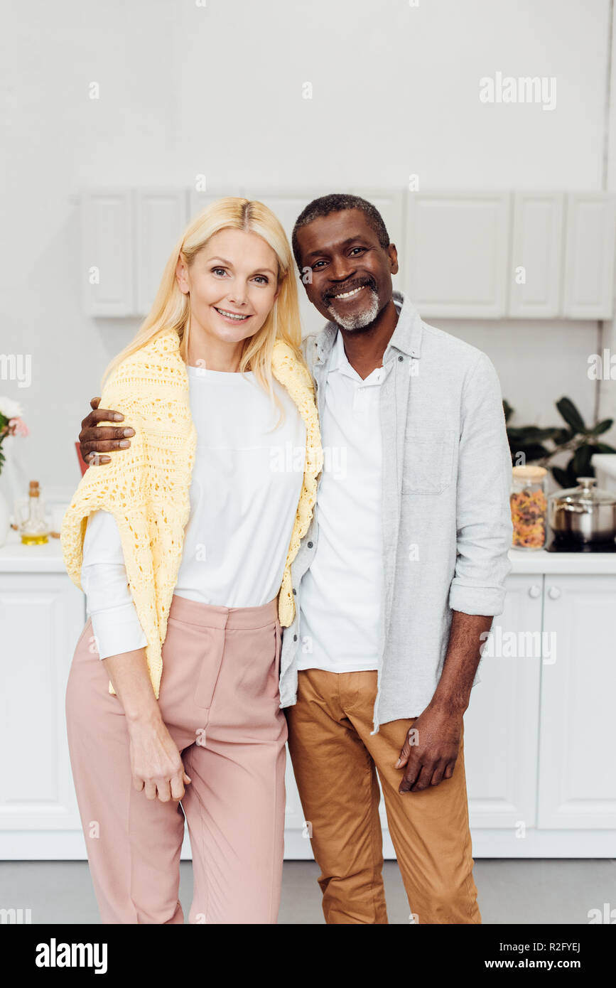 African American Man Embracing Blonde Mature Woman At Kitchen Stock Photo Alamy