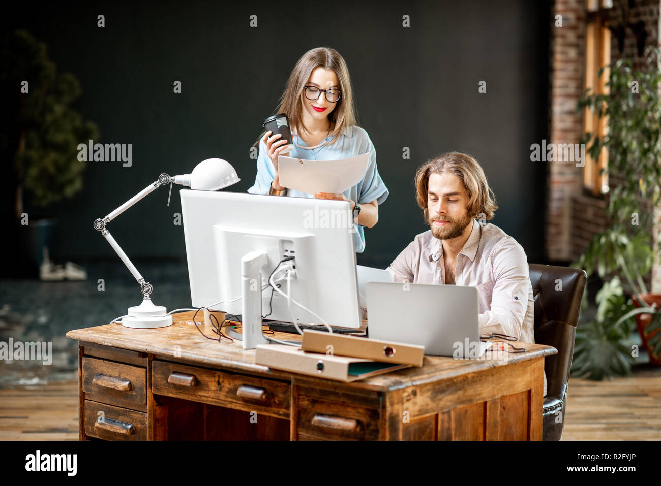 Young colleagues dressed casually working together with computers at the modern office interior Stock Photo