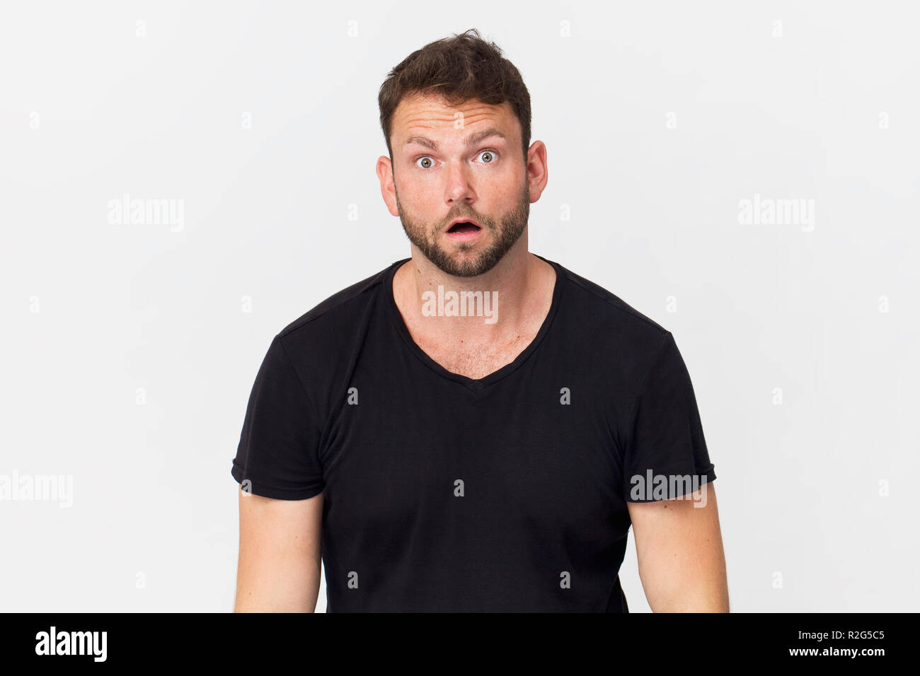 Surprised young handsome man wearing black t-shirt, isolated on white Stock Photo