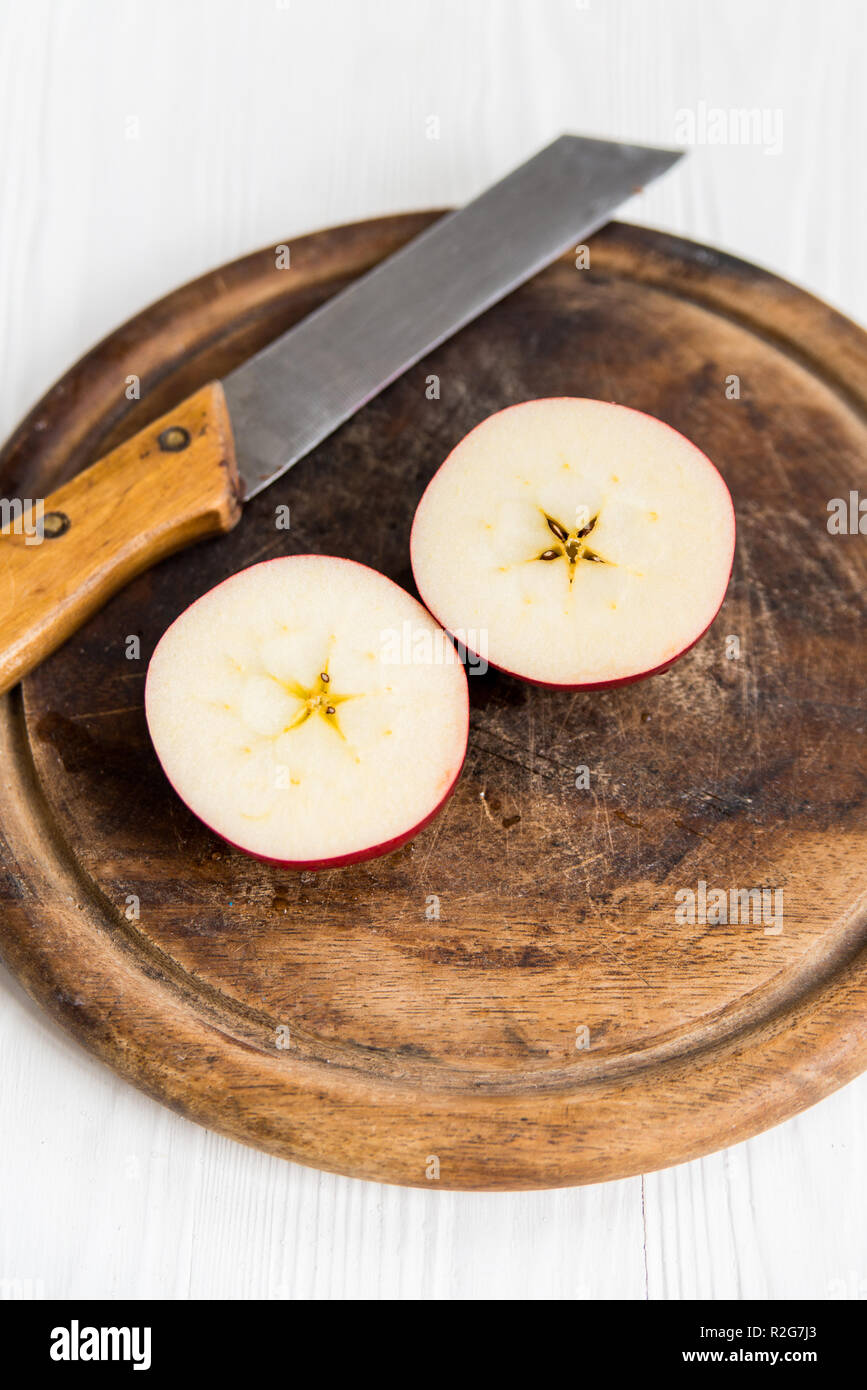 Red apple halves with knife on cutting board close Stock Photo