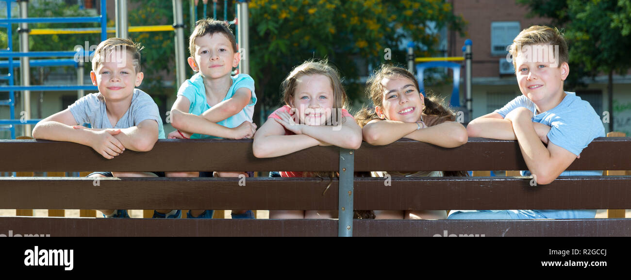 Glad children sitting on a bench at the playground Stock Photo - Alamy
