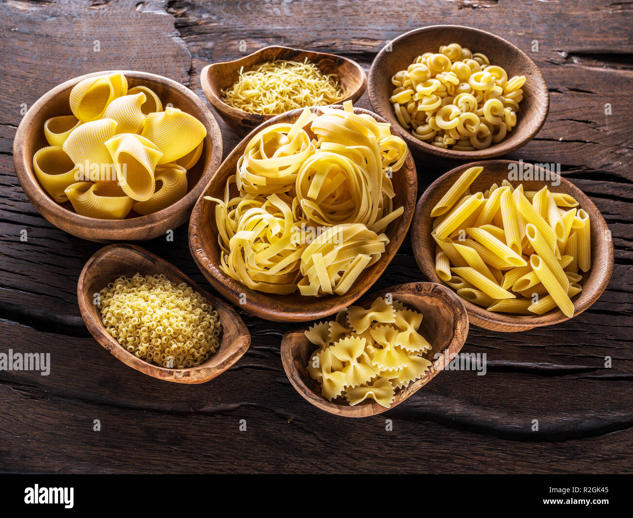 Different pasta types in wooden bowls on the table. Top view. Stock Photo