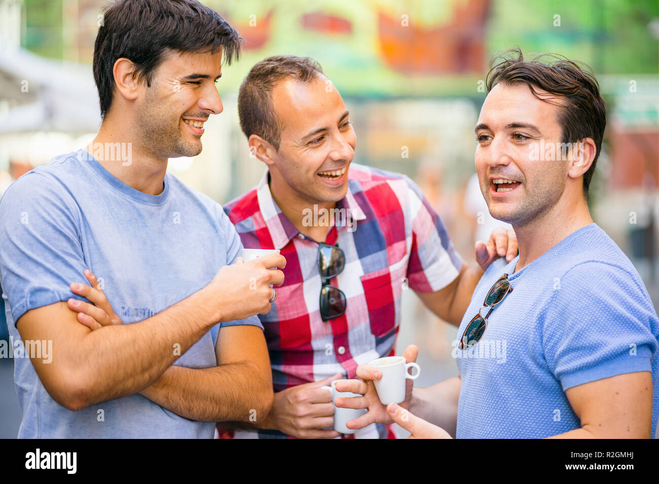 Three friends talking and having fun while drinking coffee outdoor Stock Photo